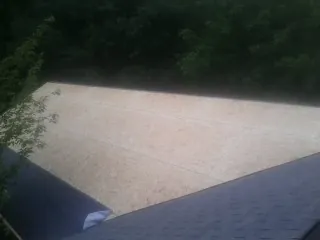 New OSB roof sheathing installed beside an existing shingle roof in Hanford