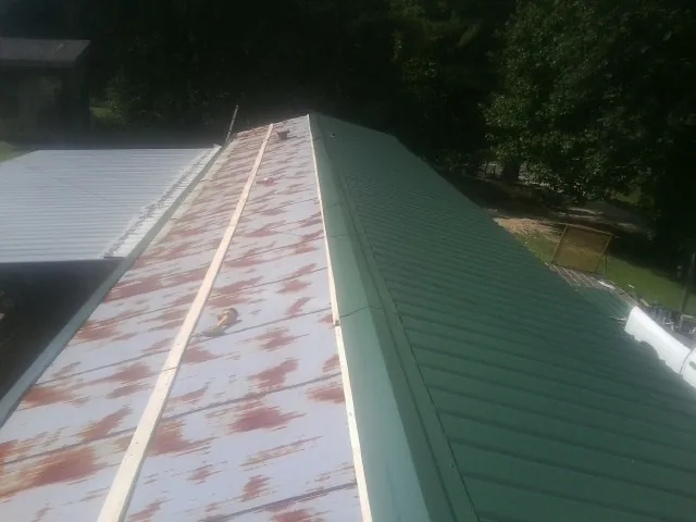 Old rusted panels beside newly installed green metal roofing — Wind Damage Roof Repair by Roofing Brothers in Hanford