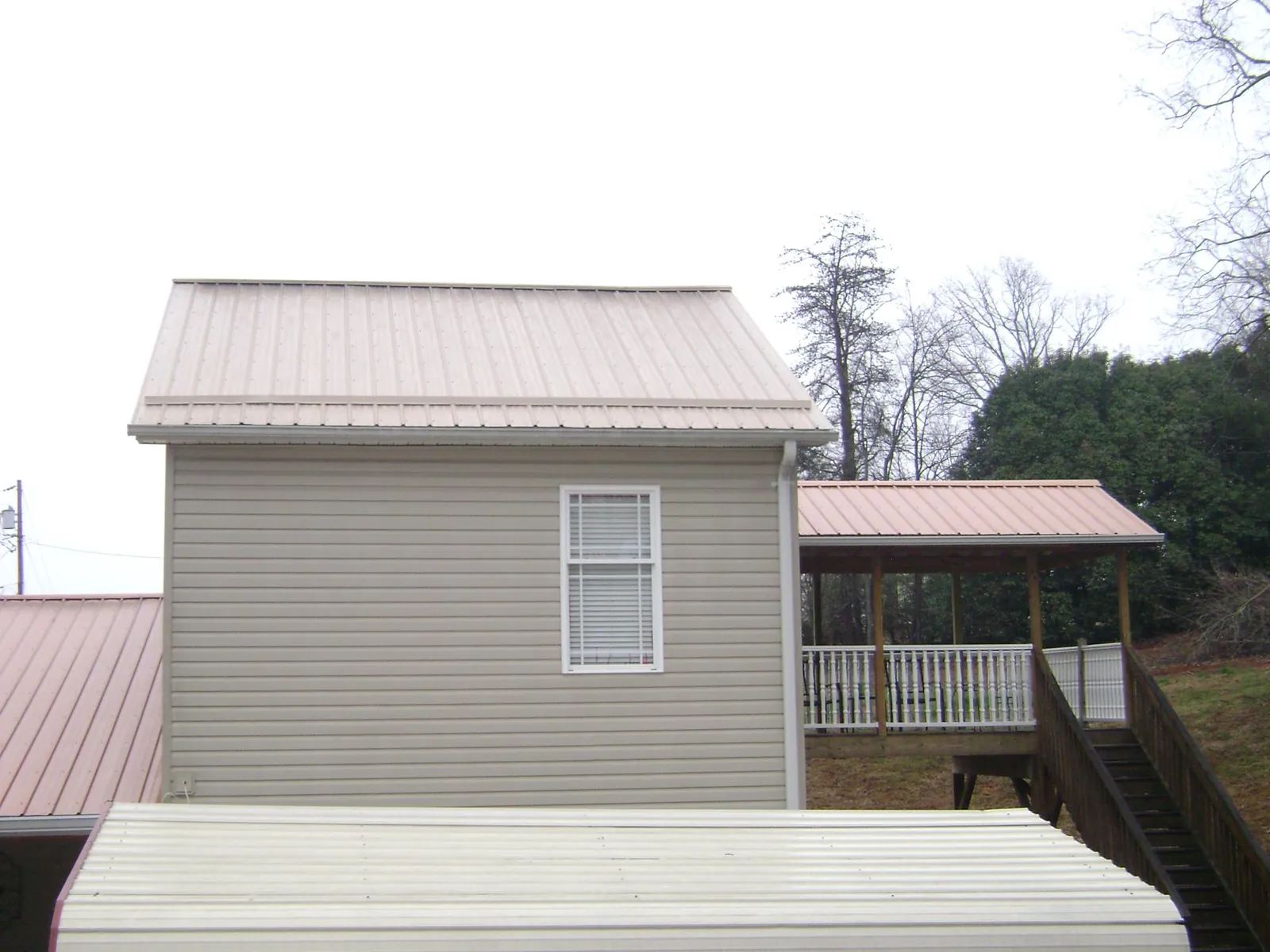 Tan metal roofs on a two story addition and attached porch, from a Roof Replacement job in Hanford
