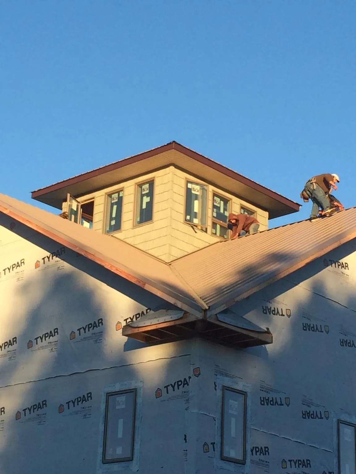 Roofers working around a rooftop cupola on a new metal roof at sunset — Roof Waterproofing in Hanford by Roofing Brothers